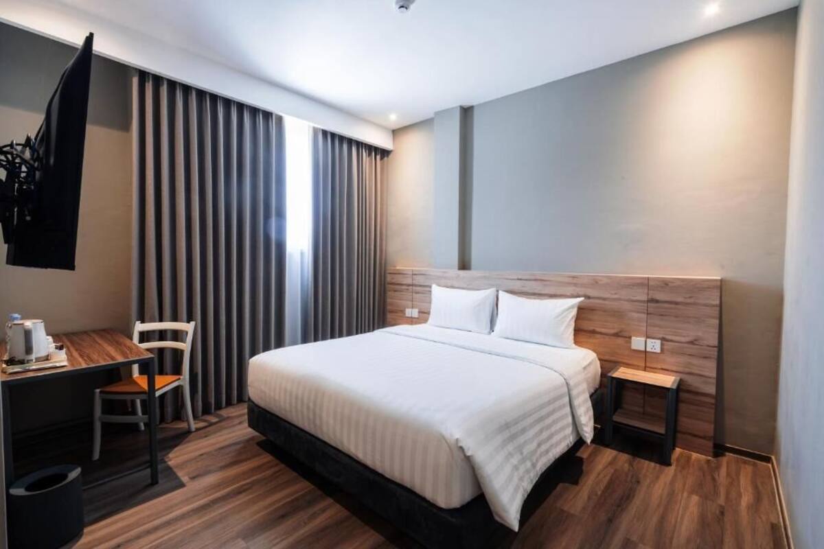 A modern hotel room with a large bed, a desk, and a chair.