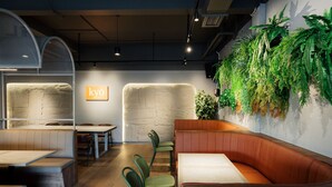 A restaurant interior with booths, high-top tables, and green chairs. - STAY KERTAPATI HOTEL (Palembang)
