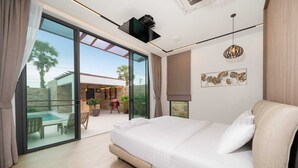 Ein modernes Schlafzimmer mit einem großen Bett, Glastüren zum Außenbereich und einem Deckenventilator.