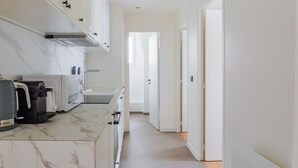 A modern kitchen with white cabinets, a marble countertop, and a built-in oven. - Blueground | Europe, view, nr Parc Monceau (Paris)