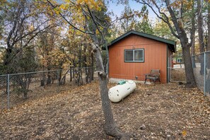 A fenced outdoor area with a wooden shed, a bench, and a white object on the ground. - Sweet  Sugarloaf Cabin (Big Bear)