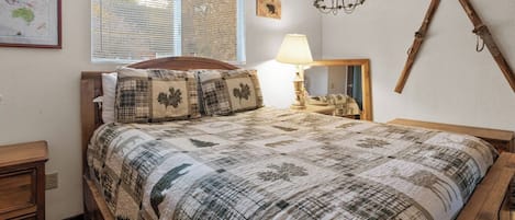 Un dormitorio con cama, mesita de noche, lámpara, mapa en la pared y espejo.