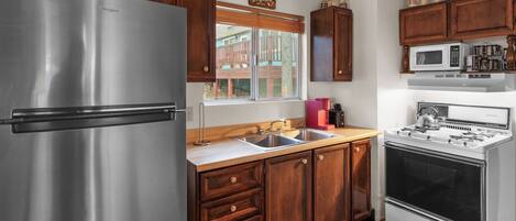 A kitchen with wooden cabinets, a stainless steel refrigerator, a gas stove, and a microwave.
