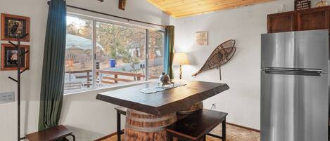 Una cocina con una mesa de madera, un refrigerador y una ventana con cortinas.