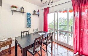 A dining area with a table and chairs, a window with red curtains, and a balcony with outdoor seating. - 2 bedroom nice apartment in Fuengirola (Fuengirola)