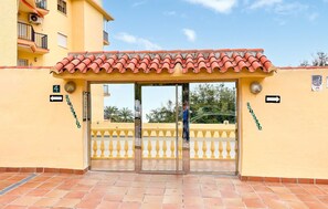 A hotel entrance with a tiled roof, a glass door, and a yellow wall. - 2 bedroom nice apartment in Fuengirola (Fuengirola)