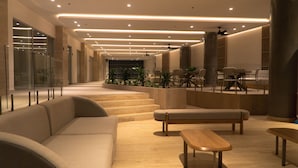En modern entréhall med en soffa, en träbänk och en matplats med stolar och ett bord.