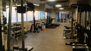 Ett gym med olika typer av träningsutrustning, inklusive löpband, hantlar och styrketräningsmaskiner.