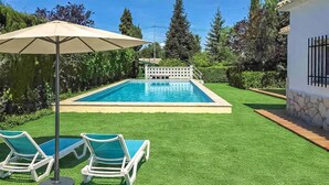 A swimming pool with two lounge chairs and an umbrella, surrounded by well-maintained grass and trees. - House in Banyeres de Mariola (Banyeres de Mariola)