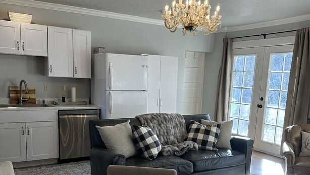 A modern living room with a sofa, ottoman, and a dining table with a vase of flowers. - Broadmoor Guest Mother-in-Law Suite (Colorado Springs)