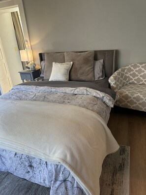 Ein Schlafzimmer mit einem Bett, einem Nachttisch, einer Lampe und einem gemusterten Teppich.