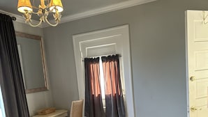 A bedroom with a bed, a desk, a chair, a mirror, and a door. - Broadmoor Guest Mother-in-Law Suite (Colorado Springs)