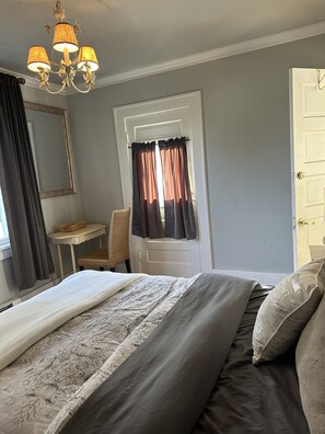 Ein Schlafzimmer mit Bett, Schreibtisch, Stuhl, Spiegel und Tür.
