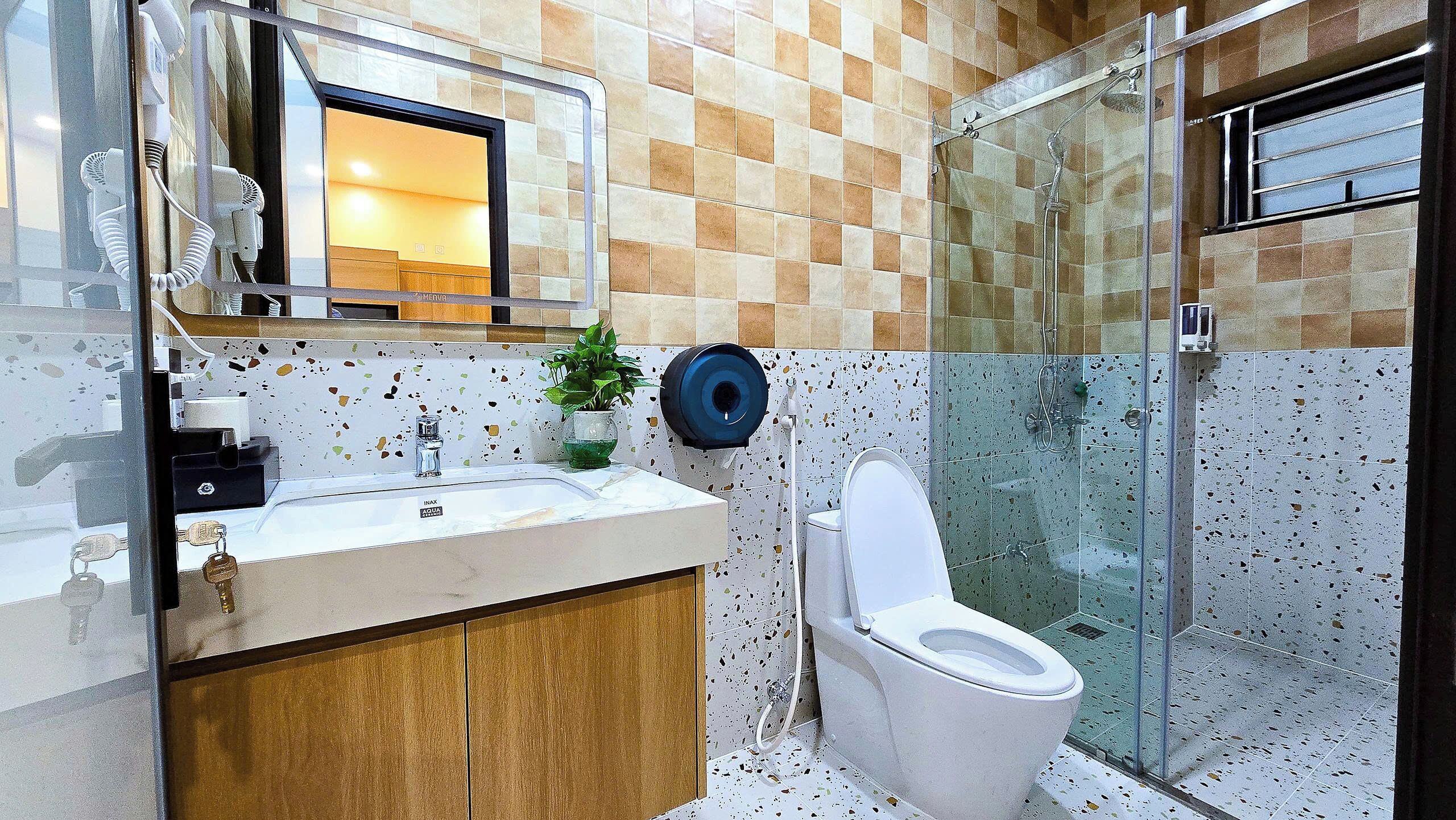 A bathroom with a sink, mirror, toilet, and shower.