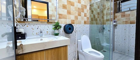 A bathroom with a sink, mirror, toilet, and shower.