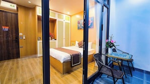 A hotel room with a bed, a small table with chairs, a window with a view, and a door with a sign. - Ha Anh Villa Ninh Binh (Hoa Lu)