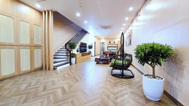 A spacious living area with a herringbone floor, a staircase, and a seating area with a coffee table and chairs. - Ha Anh Villa Ninh Binh (Hoa Lu)