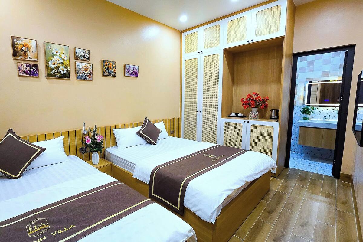 A hotel room with two beds, a small sitting area, and a kitchenette.