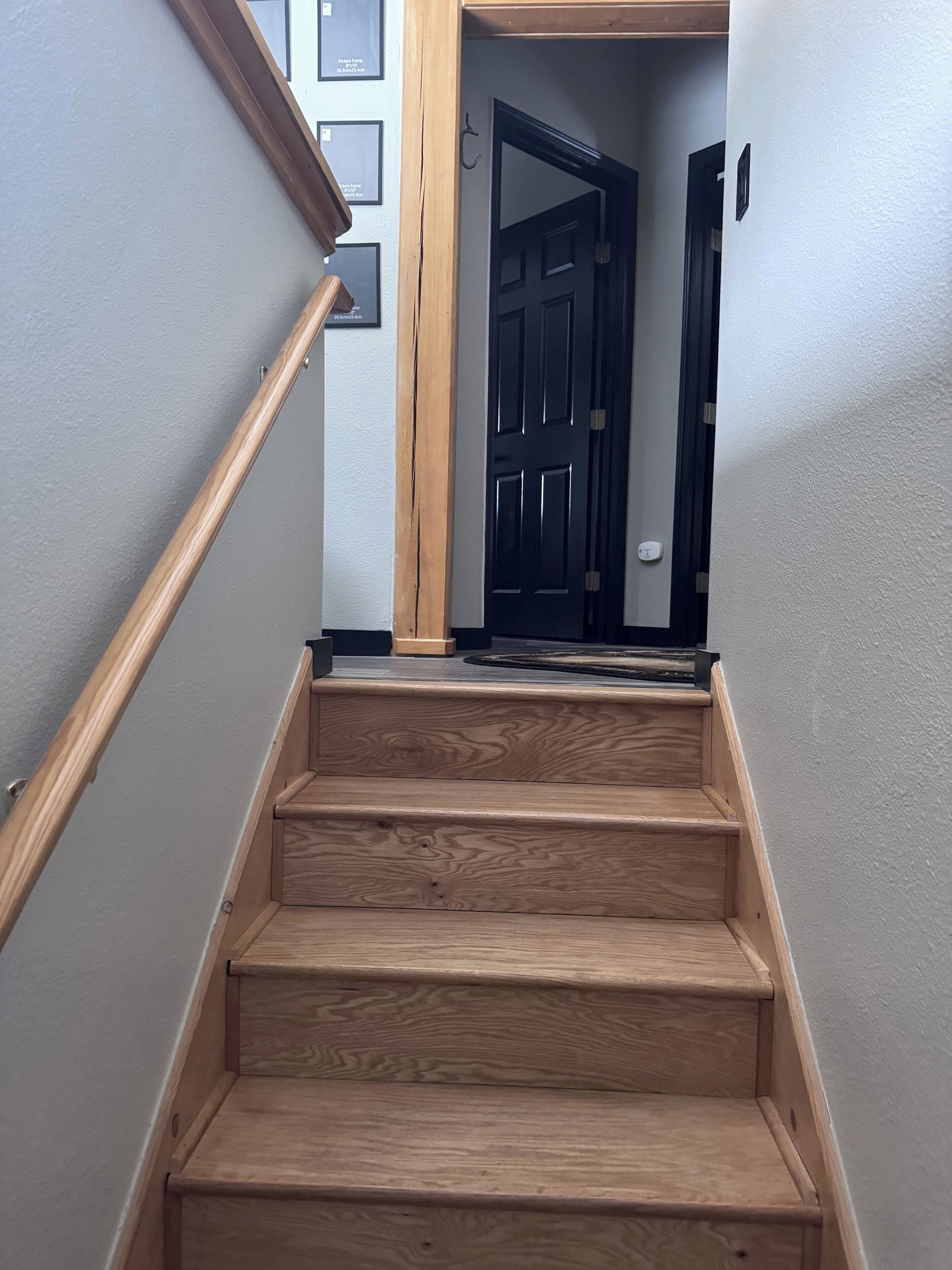 Un escalier en bois, doté d’une rampe, mène à une porte.