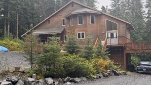 Eine Holzhütte mit Balkon, umgeben von Bäumen und einer Schotterzufahrt.