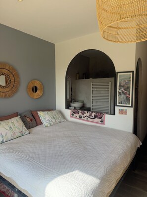 A bedroom with a large bed, a mirror, and a picture of a city scene. - Villa Serena, a haven of peace... (La Cadière-d'Azur)