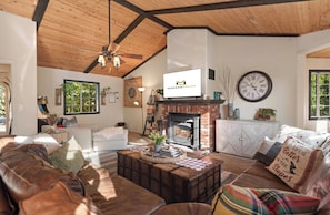 A cozy living room with a fireplace, leather sofas, and a television. - Private hot tub, Gorgeous views, Just minutes from the ski resorts & Lake (Big Bear Lake)