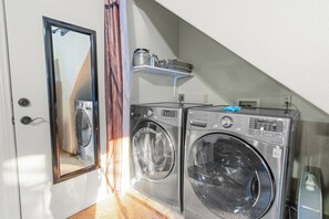 A laundry area with two washing machines, a mirror, and a shelf with items. - Private hot tub, Gorgeous views, Just minutes from the ski resorts & Lake (Big Bear Lake)