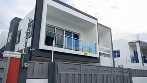 Ein modernes, zweistöckiges Haus mit Balkon, großen Fenstern und einem verschlossenen Eingang.