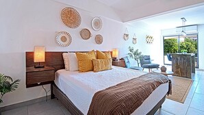 Quarto moderno com cama grande, mesas de cabeceira, decoração na parede e vista para o exterior.