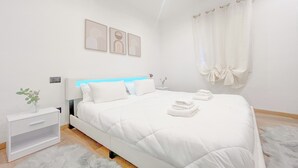Une chambre à coucher moderne avec un lit, une table de chevet et une œuvre d’art accrochée au mur.