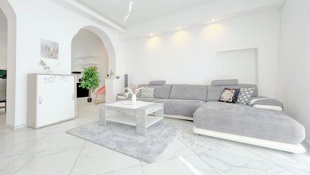 Un salon moderne avec un canapé gris, une table basse blanche et un meuble blanc.