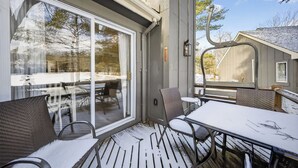 Eine überdachte Terrasse mit Tisch und Stühlen, eine Glastür und Blick ins Freie.