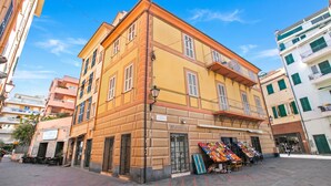 A multi-story building with a ground-floor shop and outdoor seating area. - Firpo - Apartment with Sea View, Loano, Italy (Loano)