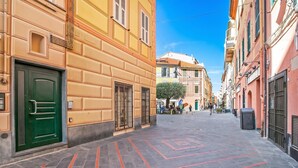 A narrow street with buildings on either side, a green door, and a tiled pavement. - Firpo - Apartment with Sea View, Loano, Italy (Loano)