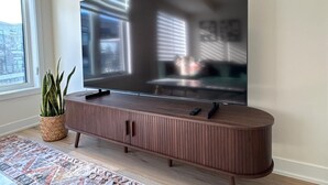 Litteänäyttöinen televisio on asennettu puiseen kaappiin, ja sen päällä on kaukosäädin.