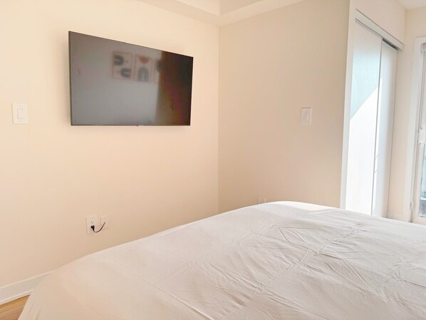A bedroom with a bed, a wall-mounted TV, and a window.