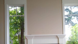 Een woonkamer met een open haard, beige muren en twee fauteuils.