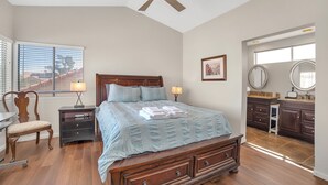 Un dormitorio con cama, mesitas de noche, un escritorio y vistas al exterior.