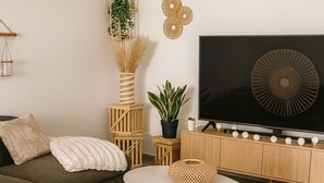 Una sala de estar moderna con un sofá, una mesa de centro redonda, un televisor y detalles decorativos en la pared.