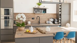 Una cocina moderna con encimera de madera, electrodomésticos de acero inoxidable y una pequeña isla con asientos.