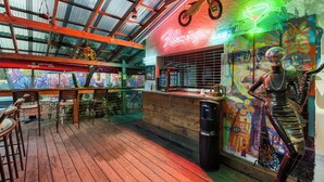 Eine Bar mit einer Neonreklame, einer Holztheke und einem Wandbild.