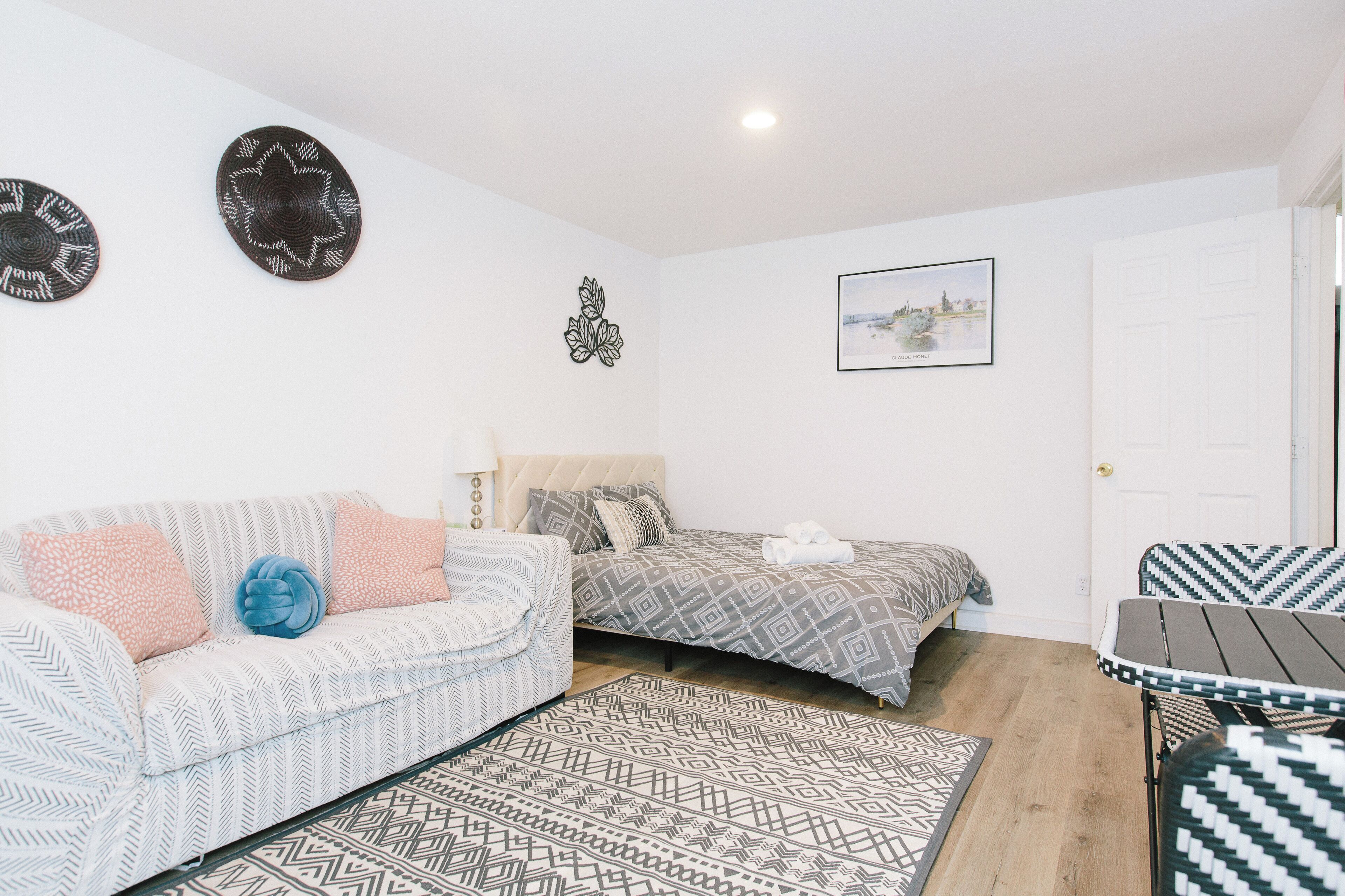 A bedroom with a bed, a sofa, a small table, and a patterned rug.