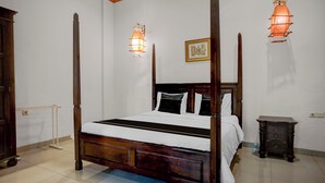 Ein Bett mit Himmelbett, ein Holzkopfstück, ein Nachttisch und zwei Wandlampen.