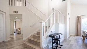 A spacious living area with a staircase, a piano, and a dining area. - Spacious 4-bedroom house in superb West Palmdale. Close to the mall. (Palmdale)