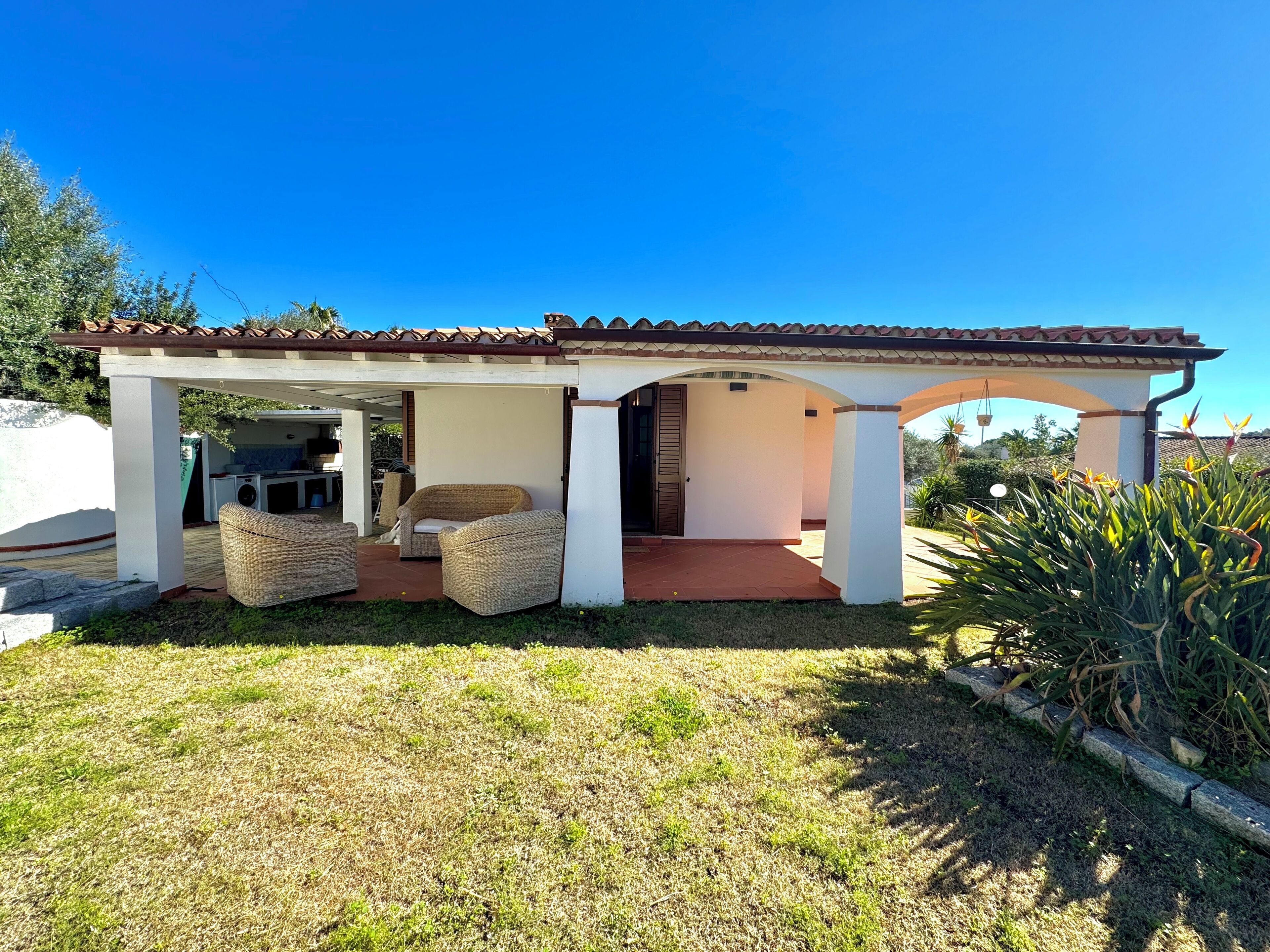 Un espacio al aire libre techado con mobiliario de mimbre, un patio y vistas del paisaje circundante.