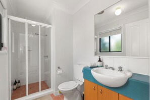 Une salle de bain avec une douche à parois de verre, des toilettes blanches, un lavabo avec un plan de travail bleu et un miroir au-dessus du lavabo.