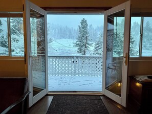 Ein Zimmer mit Blick auf eine verschneite Landschaft durch offene Glasüren.