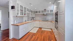 A modern kitchen with white cabinets, a wooden countertop, and a tiled backsplash.