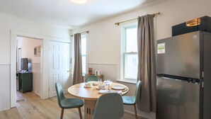 Een kleine keuken met een eettafel, stoelen, een koelkast en een magnetron.