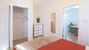 Een slaapkamer met een bed, een kaptafel, een spiegel en een potplant.